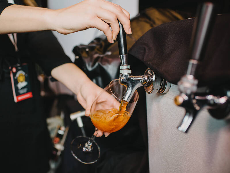 Hands on a tap pouring cider into a glass