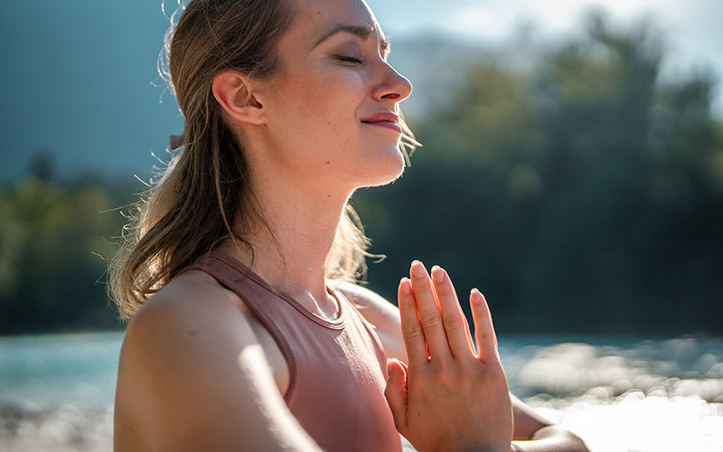 A woman practicing yoga and meditation in a forest setting during Nourish Whistler Wellness Series
